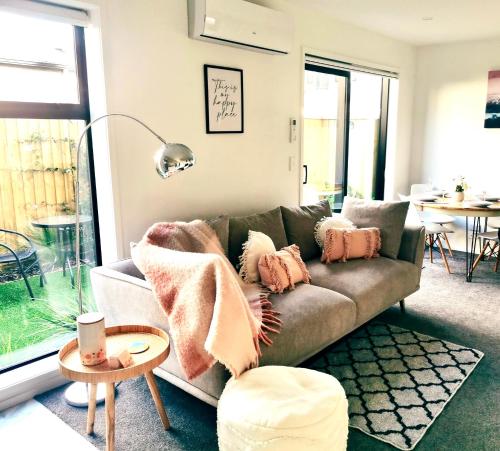 a living room with a couch with pillows on it at Home sweet home Christchurch Centre in Christchurch