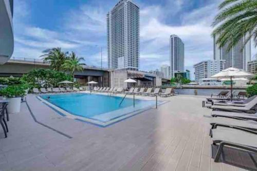 a swimming pool with lounge chairs and a building at Modern apartment in luxury condominium AB- 2 bed/2 ba in Hallandale Beach