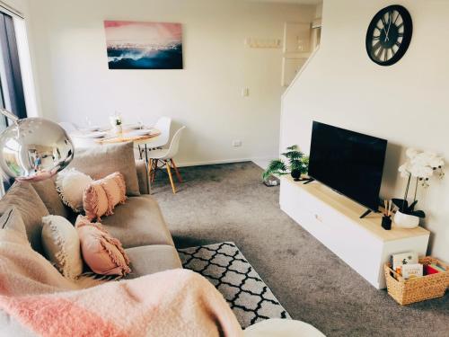 een woonkamer met een bank en een flatscreen-tv bij Home sweet home Christchurch Centre in Christchurch