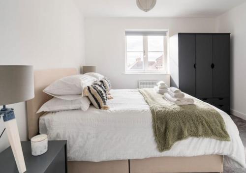 um quarto com uma cama grande com lençóis brancos e almofadas em Peniel Properties - Welwyn Garden City em Welwyn Garden City