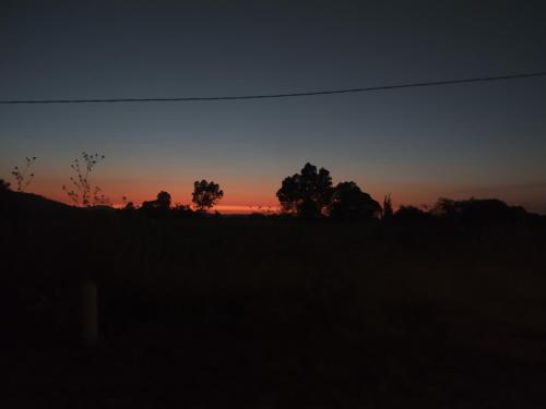 ein Sonnenuntergang auf einem Feld mit Bäumen im Hintergrund in der Unterkunft Casa de campo, a 3 minutos de Africam Safari. in Puebla