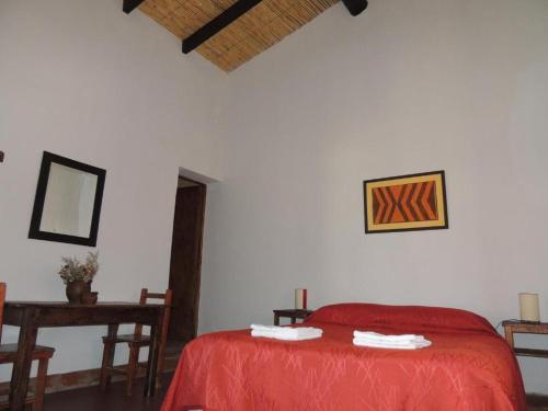 1 dormitorio con cama roja y mesa en El Rancho de Manolo en Molinos