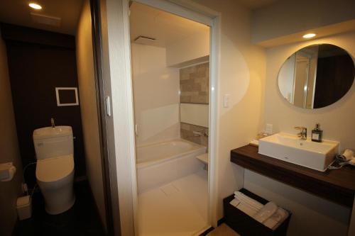 a bathroom with a sink and a toilet and a mirror at AYA Hotel in Tokyo