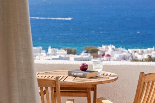 a table with an apple and a book on a balcony at Vencia Boutique Hotel in Mýkonos City