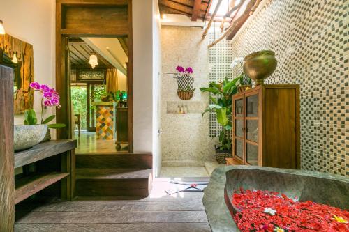 uma casa de banho com uma banheira cheia de flores vermelhas em Villa Kampung Kecil em Sanur