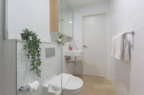 a white bathroom with a toilet and a sink at Cozy 2BR w Free Parking Near Westfield Parramatta in Sydney