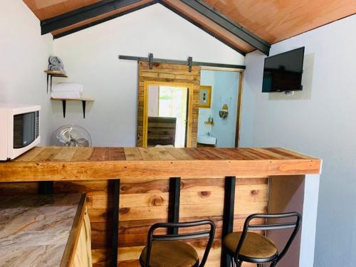 eine Holzbar mit 2 Stühlen und einem TV in der Unterkunft Cabañas del Bosque in Nandayure