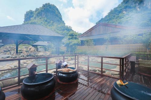 a person sitting in a bath tub on a deck at Yoko Onsen Quang Hanh in Cẩm Phả