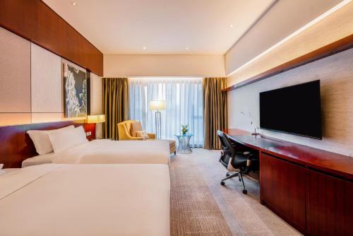 a hotel room with two beds and a desk and a television at Marco Polo Jin Jiang in Jinjiang