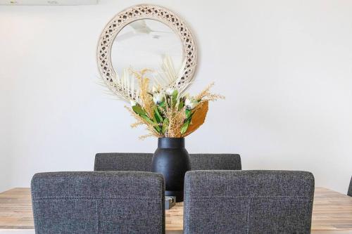 a table with a vase with flowers and a mirror at Captain's Lookout - Penthouse Living at Cullen Bay in Darwin