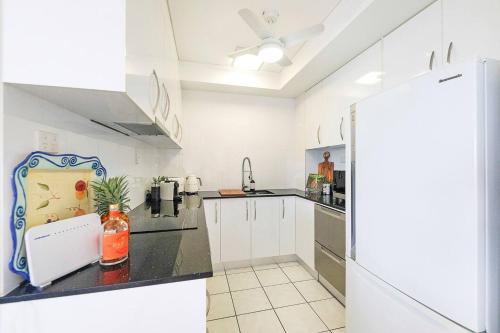 a kitchen with white cabinets and a refrigerator at Captain's Lookout - Penthouse Living at Cullen Bay in Darwin