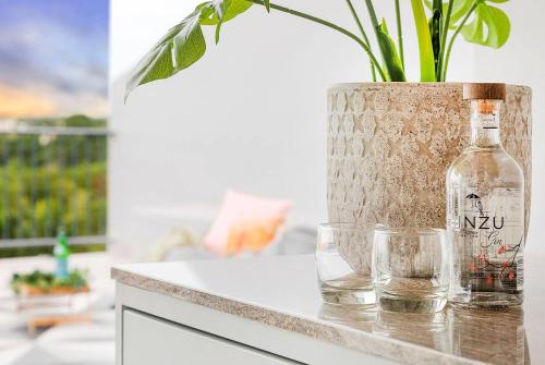 a bottle and two glasses on a counter with a plant at Captain's Lookout - Penthouse Living at Cullen Bay in Darwin