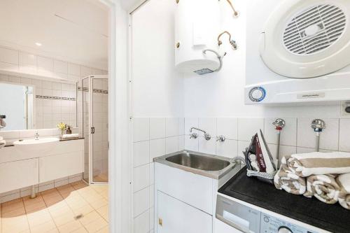 a small white kitchen with a sink and a mirror at Captain's Lookout - Penthouse Living at Cullen Bay in Larrakeyah