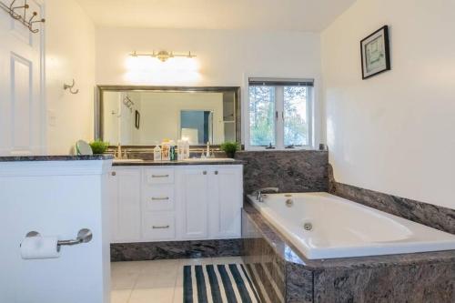 a bathroom with a large tub and a sink at Spacious Home Near Herndon/Dulles Airport/Ashburn in Sterling