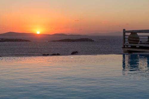 a person sitting on a bench watching the sunset at Vencia Boutique Hotel in Mýkonos City