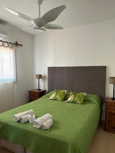 Un dormitorio con una cama verde con toallas. en Aires del cerro en Salta