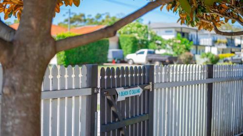 a white picket fence with a street sign on it at Harrys Pet Friendly Holiday House in Nelson Bay