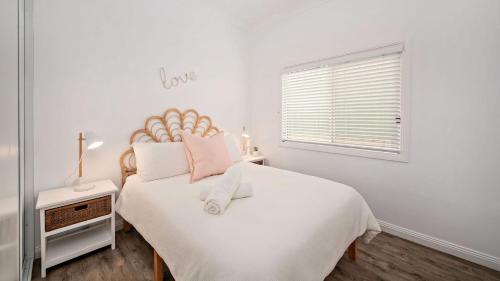 Un dormitorio con una gran cama blanca y una ventana en Harrys Pet Friendly Holiday House en Nelson Bay