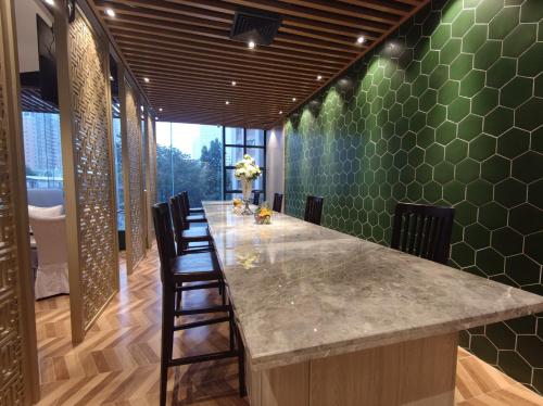 a kitchen with a long counter with chairs and green tiles at Guangzhou Good International Hotel in Guangzhou