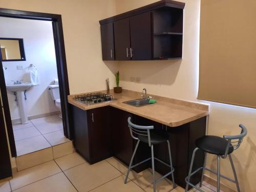 a kitchen with a sink and a counter with stools at Hgen Rooms & Suites in Los Mochis