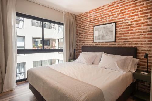 Un dormitorio con una pared de ladrillo y una cama grande en Stunning Bright Apt La Galerie San Telmo - 229 - en Buenos Aires