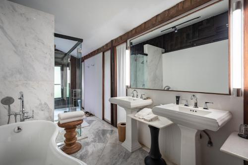 a bathroom with two sinks and a tub and a mirror at Villa Mahabhirom - SHA Plus in Chiang Mai