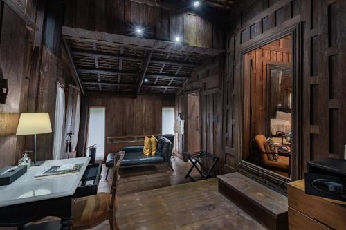 a living room with wooden walls and a table and a couch at Villa Mahabhirom - SHA Plus in Chiang Mai