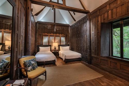 a bedroom with two beds and a table and chairs at Villa Mahabhirom - SHA Plus in Chiang Mai