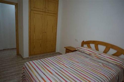 1 dormitorio con 1 cama y puerta de madera en Apartamento La Mata, en La Mata