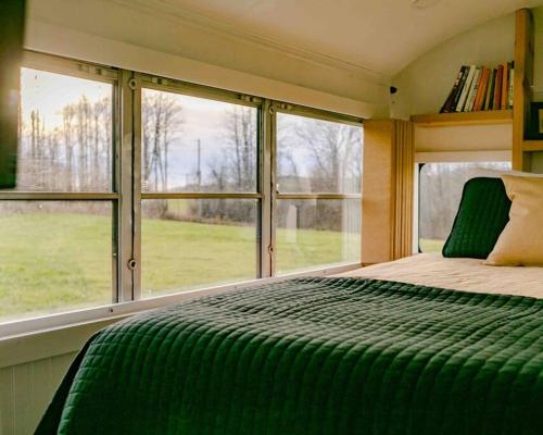 1 dormitorio con 1 cama verde grande frente a las ventanas en Serene Bus Getaway Among Rolling Farm Land en Granville
