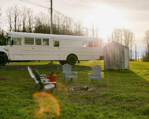 un autobús blanco estacionado en un campo con sillas en Serene Bus Getaway Among Rolling Farm Land en Granville