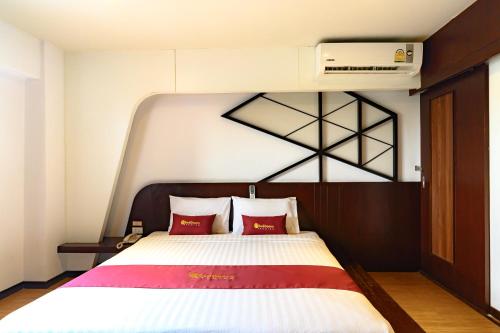a bedroom with a large bed with red pillows at Coco Hotel in Bangkok
