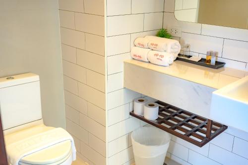 a bathroom with a toilet and towels on a shelf at Coco Hotel in Bangkok