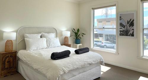 a bedroom with a white bed with two black towels on it at Stays on Main in Narrabri