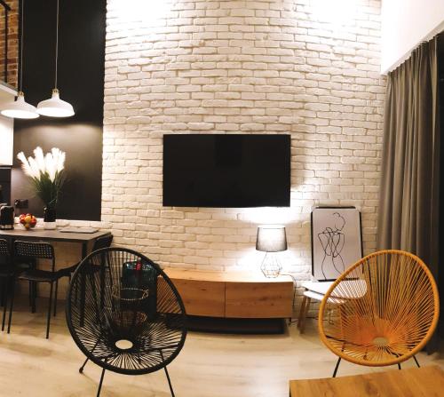 a living room with two chairs and a tv on a brick wall at Lividus Czarna Mewa in Świnoujście