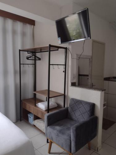 um quarto com uma cadeira e uma televisão na parede em Studio no Centro em Araxá