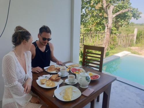 un hombre y una mujer sentados en una mesa con desayuno en Giri Villa, en Tangalle