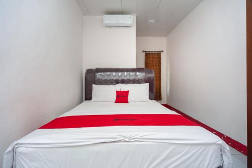 Ce lit se trouve dans un dortoir doté d'une couverture rouge. dans l'établissement RedDoorz Syariah near Tugu Juang Jambi 3, à Jambi