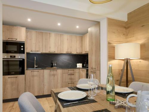 - une cuisine avec une table et des chaises ainsi qu'une bouteille de vin dans l'établissement Superbe appartement neuf - 8 pers - Courchevel 1650 - Pieds des pistes - FR-1-631-130, à Courchevel
