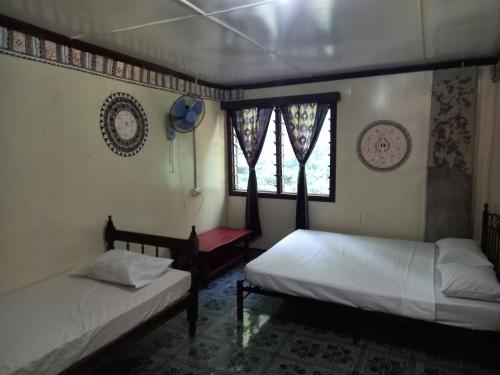 two beds sitting in a room with a window at WAI MAKARE HOMESTAY ROOM 2 in Naviti Island