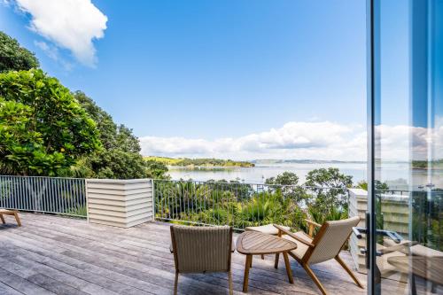 a balcony with chairs and a view of the water at Koi Waiheke with private beach access and mooring in Omiha