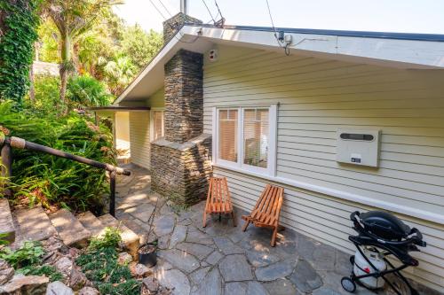a house with two chairs and a stroller next to it at Koi Waiheke with private beach access and mooring in Omiha