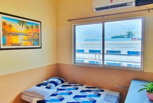 a bedroom with a bed and a window and a table at RedDoorz @ RSL Transient House Iloilo in Iloilo City