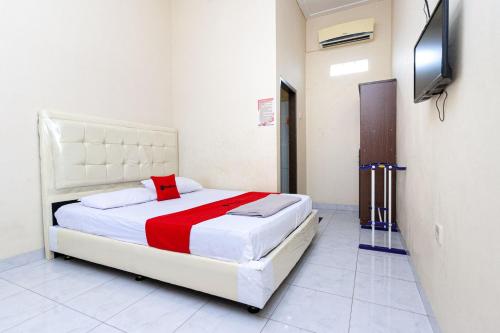 um quarto com uma cama e uma televisão na parede em RedDoorz @ Jalan Sidomuncul 2 Jambi em Jambi