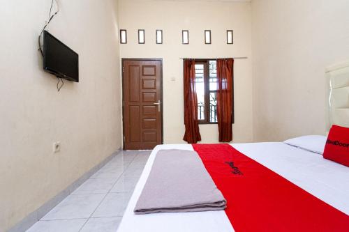 a bedroom with a red blanket on a bed at RedDoorz @ Jalan Sidomuncul 2 Jambi in Jambi