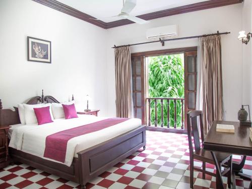 um quarto com uma cama, uma secretária e uma janela em Chateau d'Angkor La Residence em Siem Reap