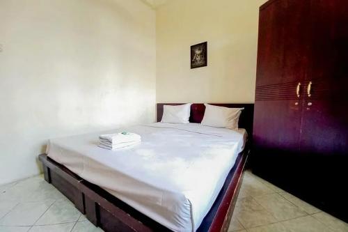 1 dormitorio con 1 cama grande con sábanas blancas en Graha Ara Homestay Syariah RSUD Dr Soetomo Surabaya Mitra RedDoorz, en Surabaya