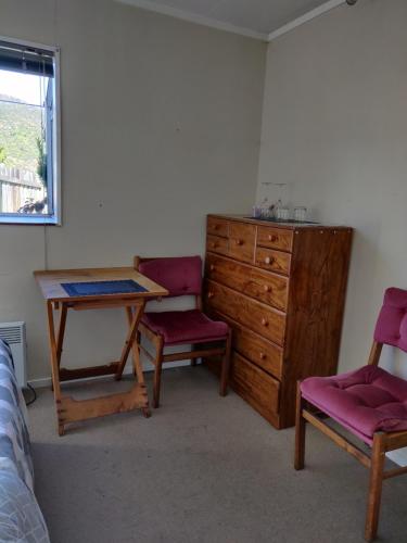 um quarto com uma mesa, 2 cadeiras e uma cómoda em wanaka plantation road room em Wanaka