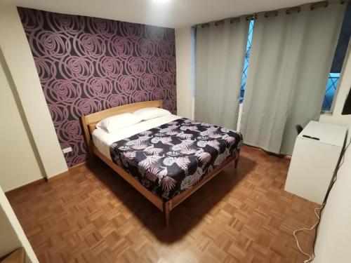 1 dormitorio con 1 cama con pared morada en Dormitorio Amplio cerca de Parque Carolina, en Quito