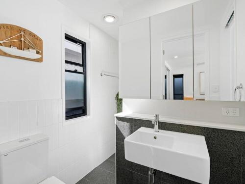 a white bathroom with a sink and a mirror at 1 Bedroom Modern Townhouse in Casuarina in Casuarina
